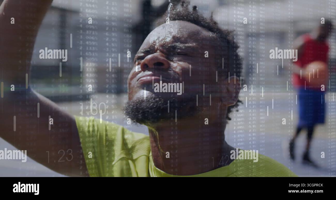 Uomo in camicia al neon che versa acqua dalla bottiglia in testa in un campo all'aperto, con copertura finanziaria Foto Stock