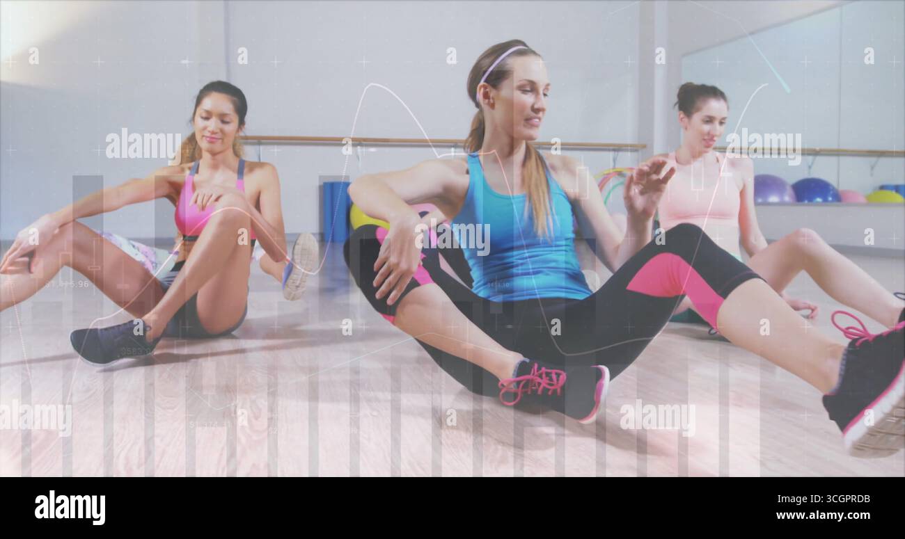 Stretching di tre donne che indossano abbigliamento atletico sedute sul pavimento dello studio, con sbarre e palle da ginnastica Foto Stock