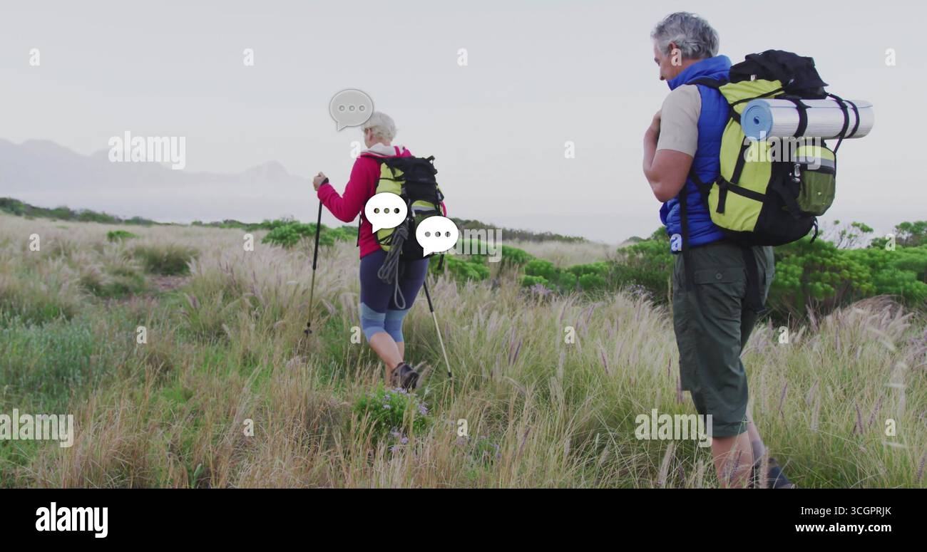Coppia escursionistica che esplora le dune costiere con pali da trekking zaini stivali e materassino arrotolato Foto Stock