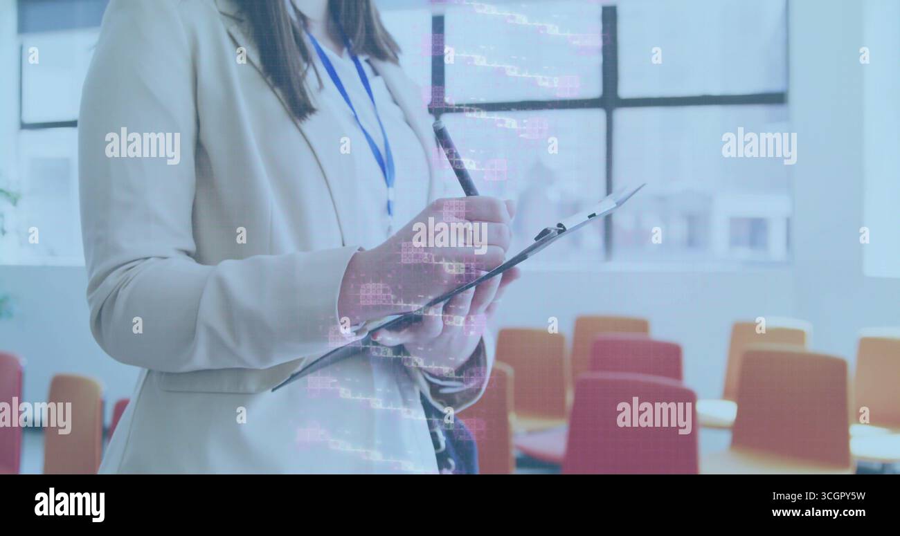 Donna d'affari in piedi che tiene in mano appunti e penna nell'aula di formazione con sedie, distintivo, sovrapposizione codice Foto Stock