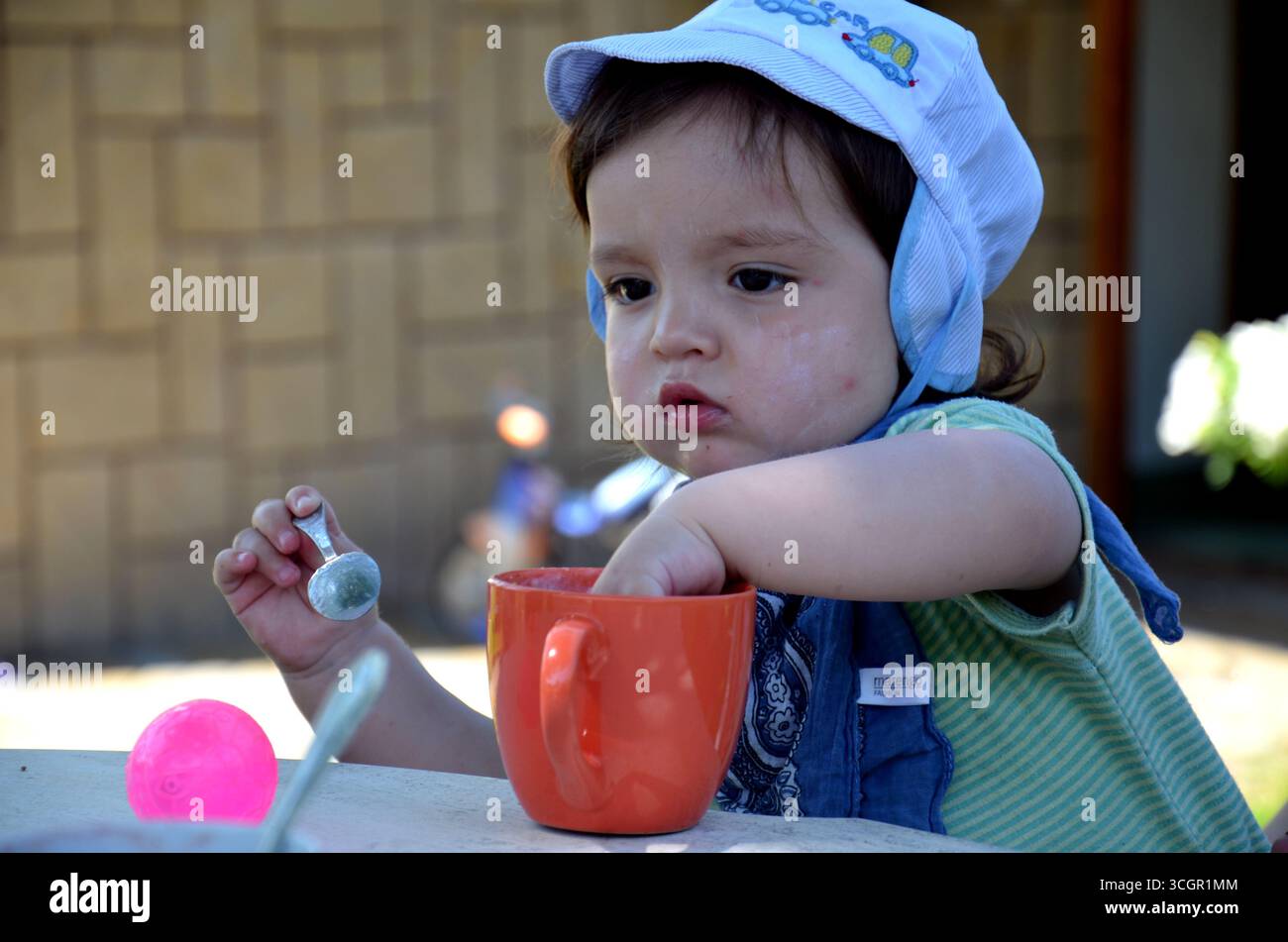 Un allegro bimbo di due anni mangia guardando direttamente l'obiettivo della fotocamera. Il bambino sorride con gioia, creando un momento naturale e caldo Foto Stock