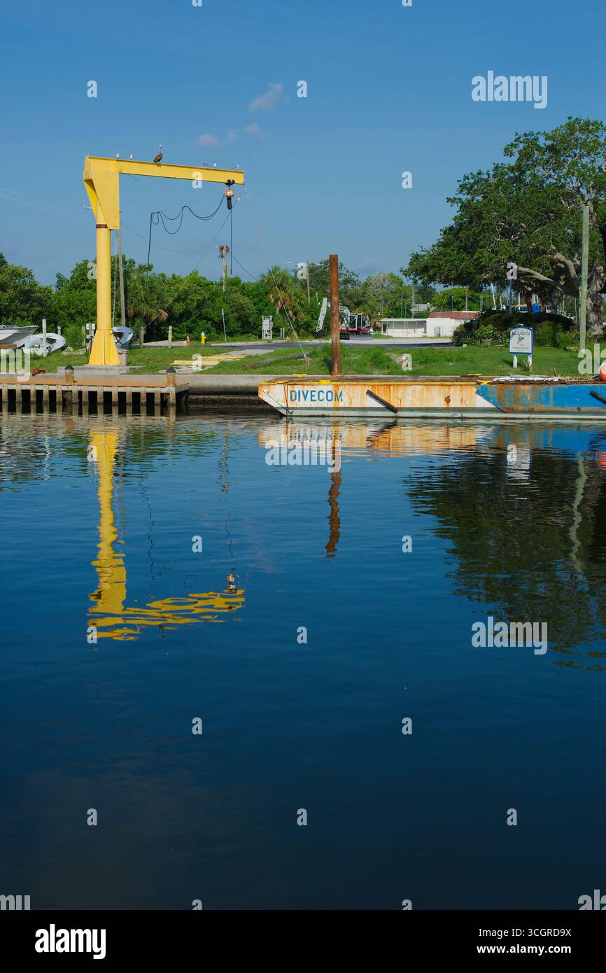 Scena Rustic Waterfront con riflessi e cielo blu. Solo per uso editoriale, gulfport, fl, usa 29 agosto 2025 molo tranquillo con chiatta blu arrugginita, V Foto Stock