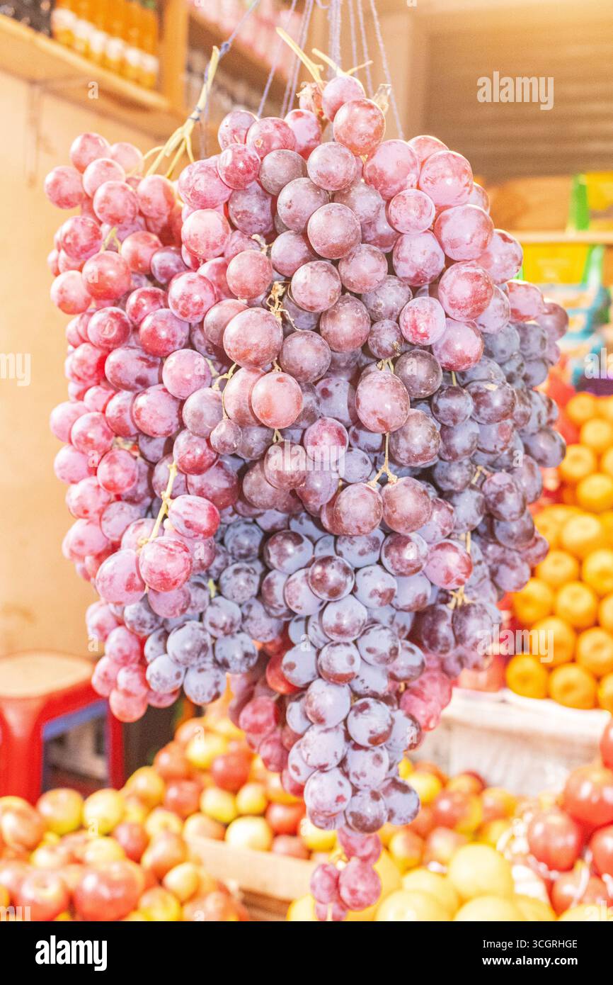 Grappolo di uva rossa fresca appeso al mercato locale della frutta Foto Stock
