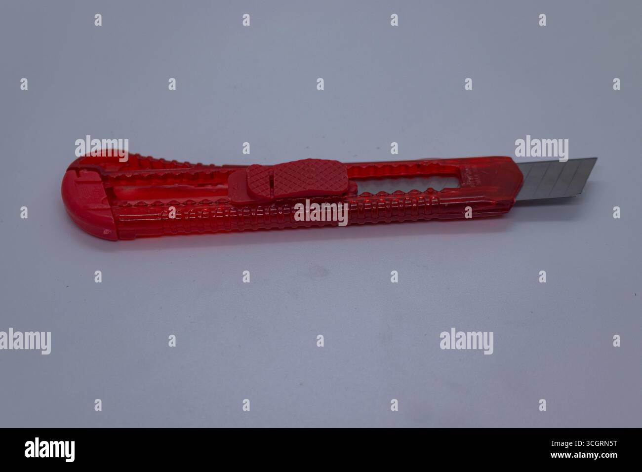 Coltello multiuso rosso con lama retrattile per l'uso in ufficio e nell'artigianato su sfondo bianco, Foto Stock