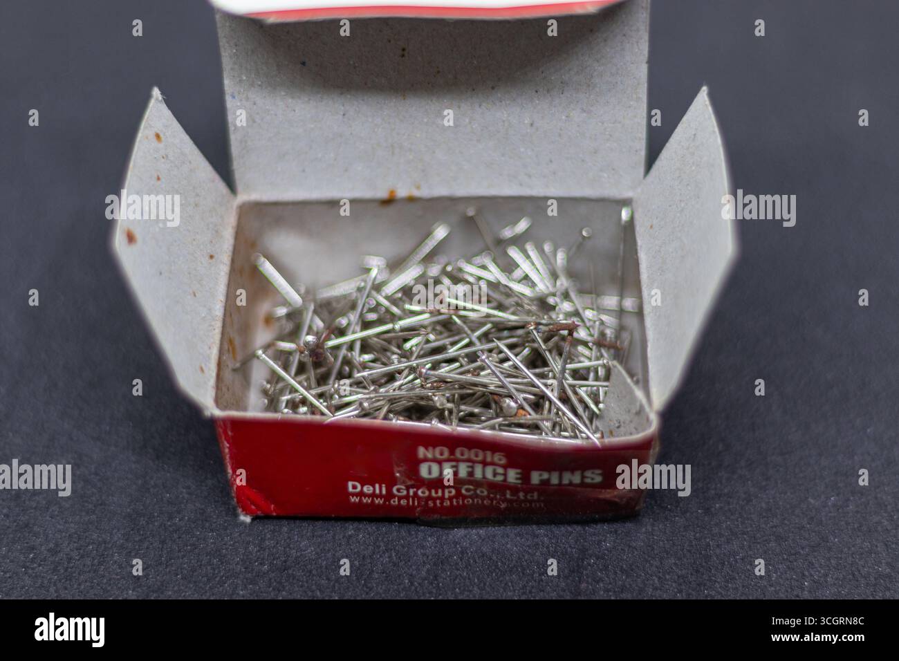 Scatola di perni da ufficio rustici con chiodi argento su sfondo in tessuto scuro Foto Stock