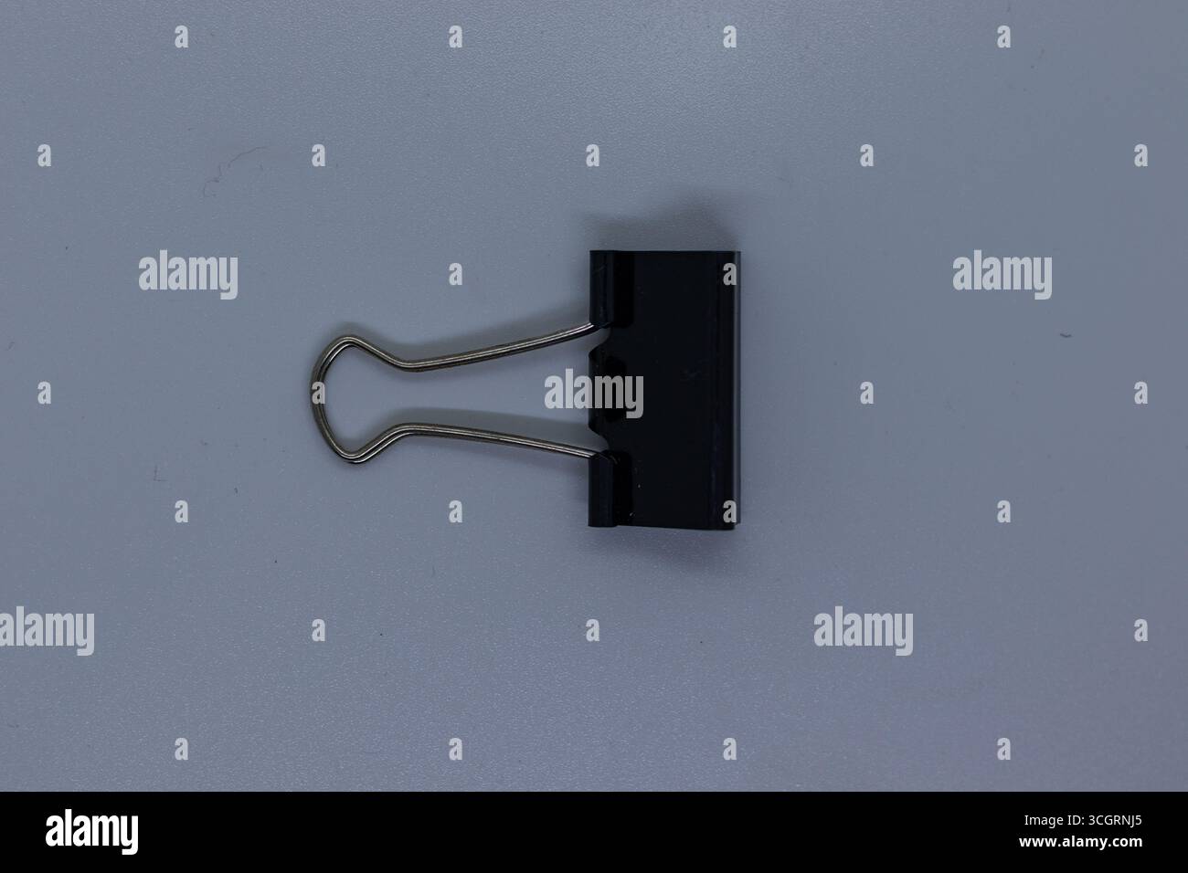Clip legante semplice nera con manici argentati su superficie bianca pulita Foto Stock