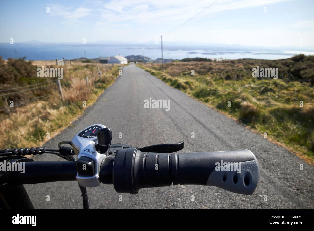 pedalando su una piccola bicicletta elettrica lungo la strada di campagna arranmore arainn mhor con vista sulla terraferma della contea di donegal, repubblica d'irlanda Foto Stock