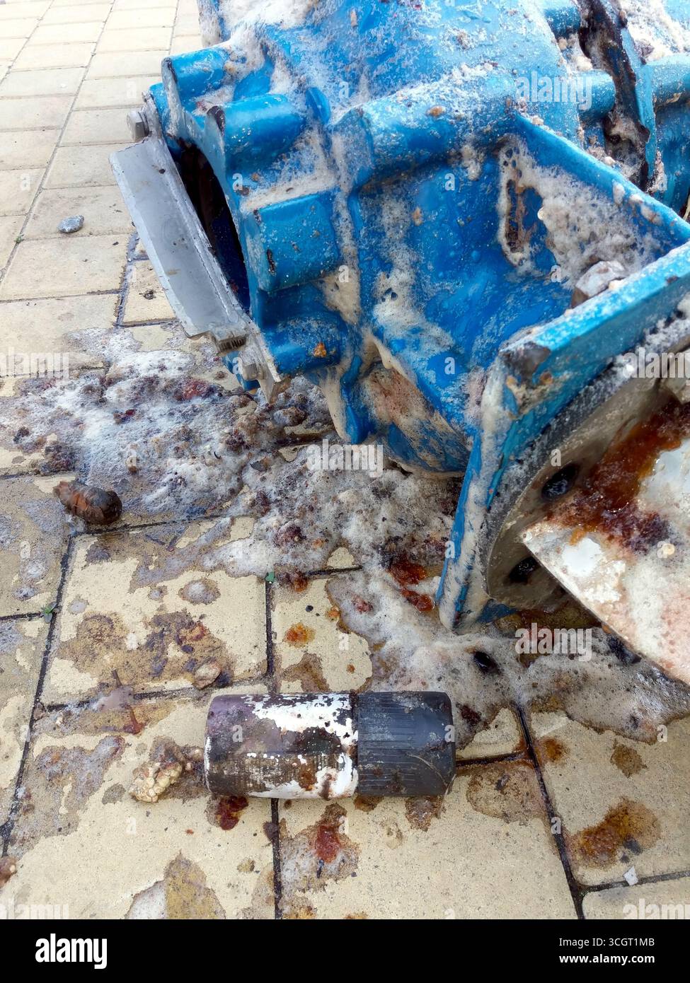 In mezzo all'acqua sporca e ai detriti su un'area piastrellata viene mostrata una pompa sommersa per la pulizia, a indicare che è in corso un processo di pulizia. Foto Stock