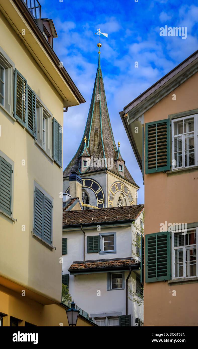 L'iconica torre dell'orologio della Chiesa di San Pietro incorniciata da edifici storici circostanti nella città vecchia o nell'Altstadt di Zurigo, Svizzera Foto Stock