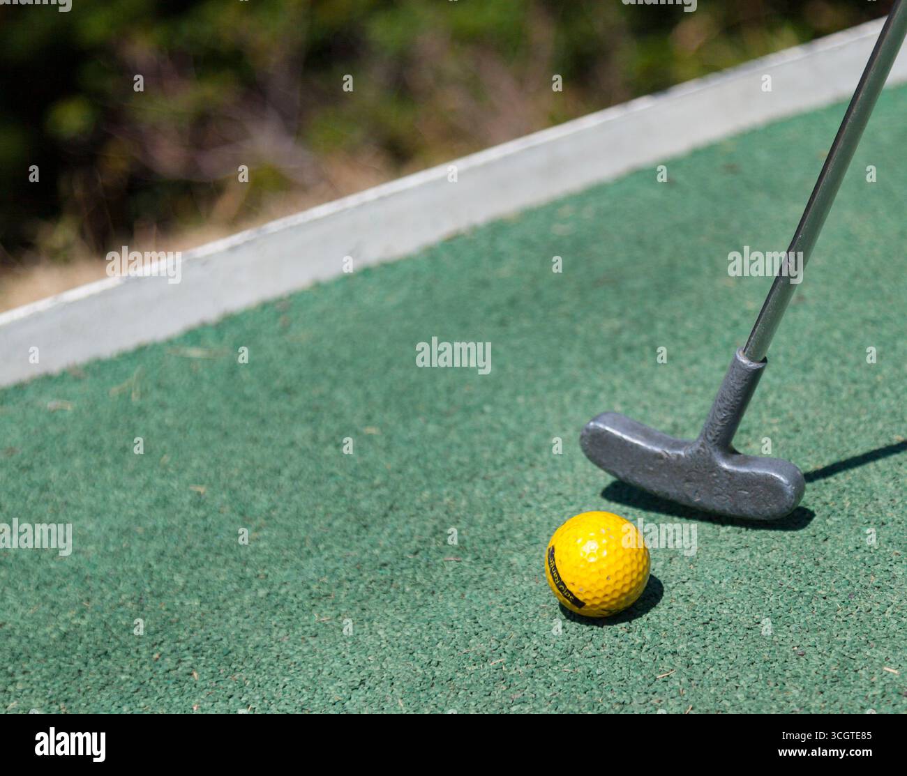 Una mazza da golf e una palla da golf gialla su erba artificiale astro Foto Stock