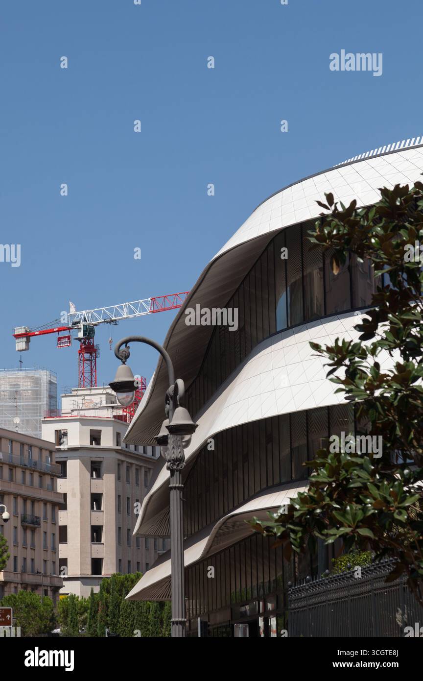 Contrasto tra un edificio moderno ed elegante e vecchi edifici regolari e una gru Foto Stock