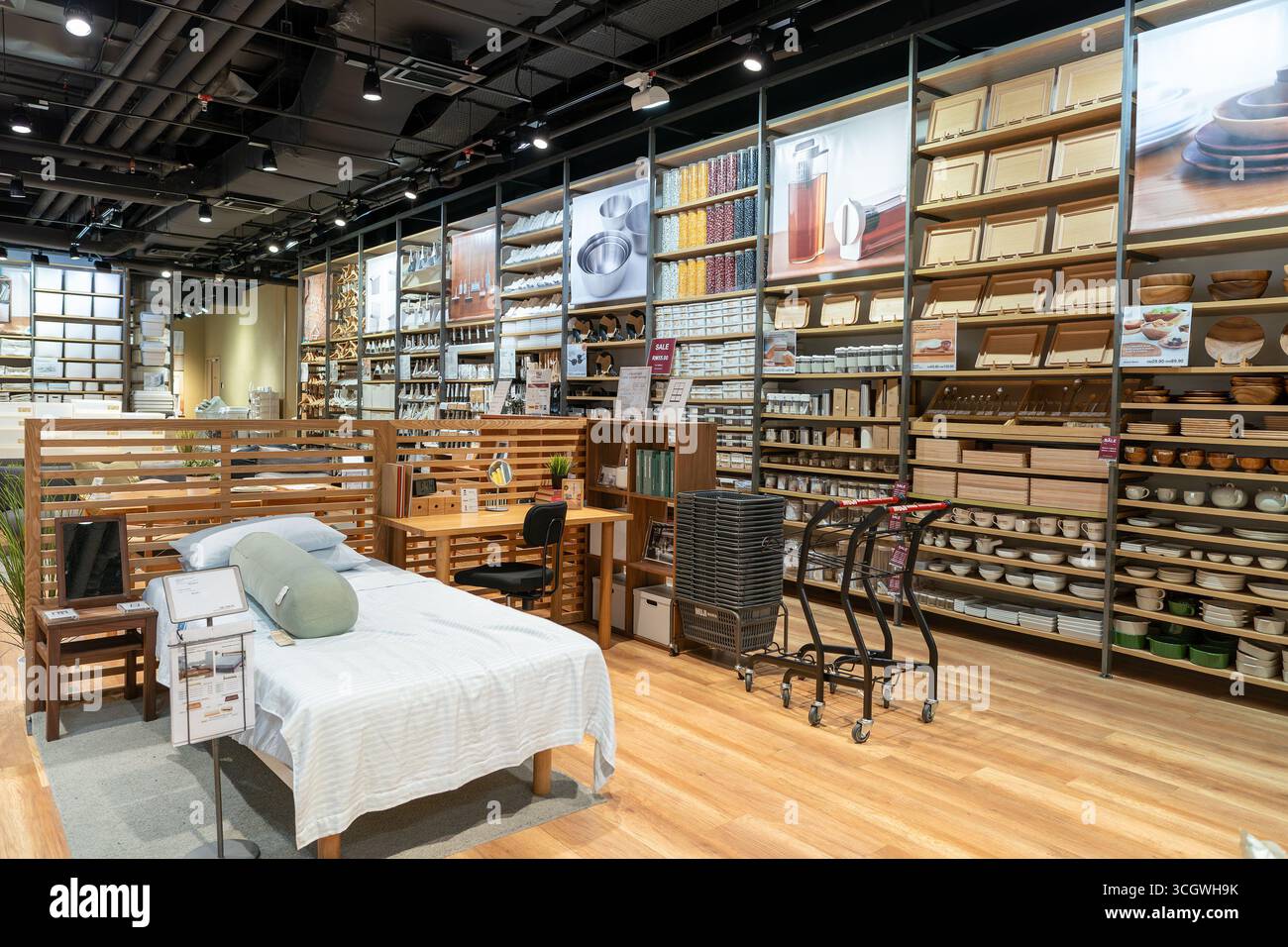 Petaling Jaya, Malesia - 14 luglio 2024: Mostra biancheria da letto con un letto preparato, con gli articoli di prima necessità sugli scaffali sullo sfondo, come si vede nel negozio Muji Foto Stock