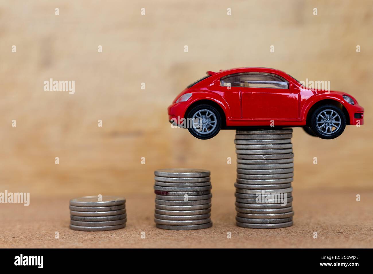Red Toy Car su pile di monete. Simbolo del budget del veicolo e della pianificazione finanziaria Foto Stock
