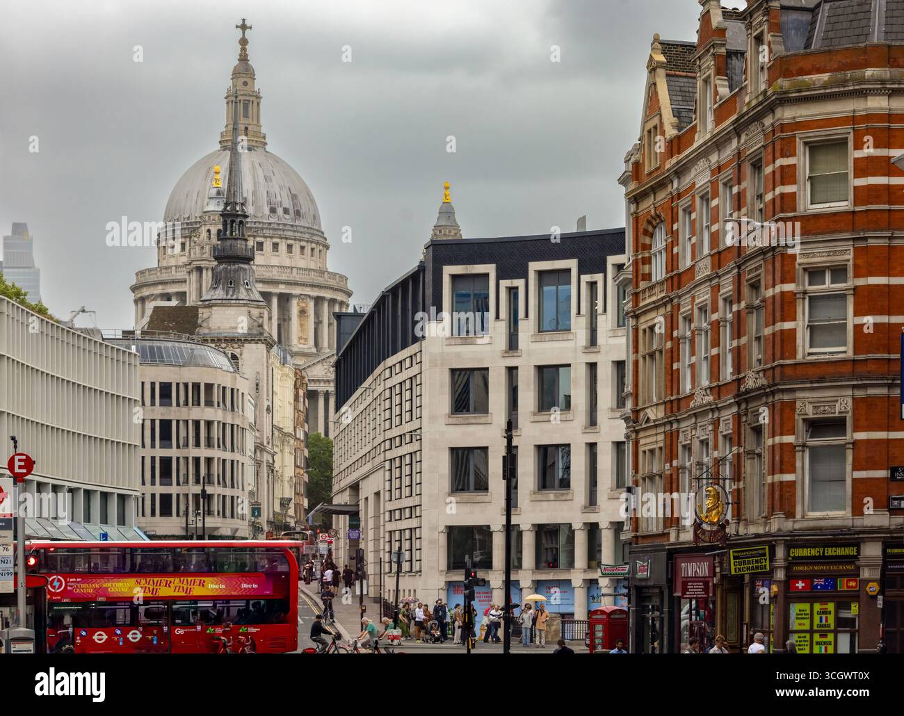 Scena di strada vicino alla Cattedrale di St Paul, Londra, con la cupola, un autobus rosso a due piani e un mix di edifici storici e moderni Foto Stock