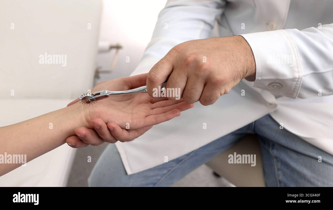 Neurologia. Controllo dei riflessi femminili delle mani usando la ruota ad aghi neurologica in una clinica neurologica, primo piano Foto Stock