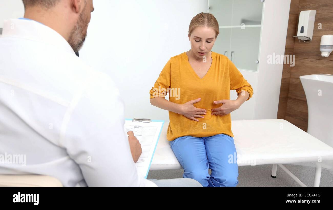 Donna con dolore addominale durante un consulto con gastroenterologa che controlla le condizioni dei suoi organi interni, come stomaco, fegato, gallbladd Foto Stock