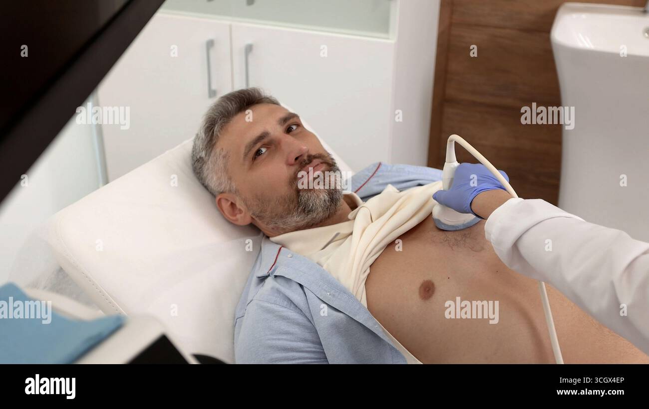 Esame di ecografia cardiaca per pazienti di sesso maschile con specialista di ecografia durante l'esame medico. Esame di salute del cuore con la macchina di scansione a ultrasuoni Foto Stock