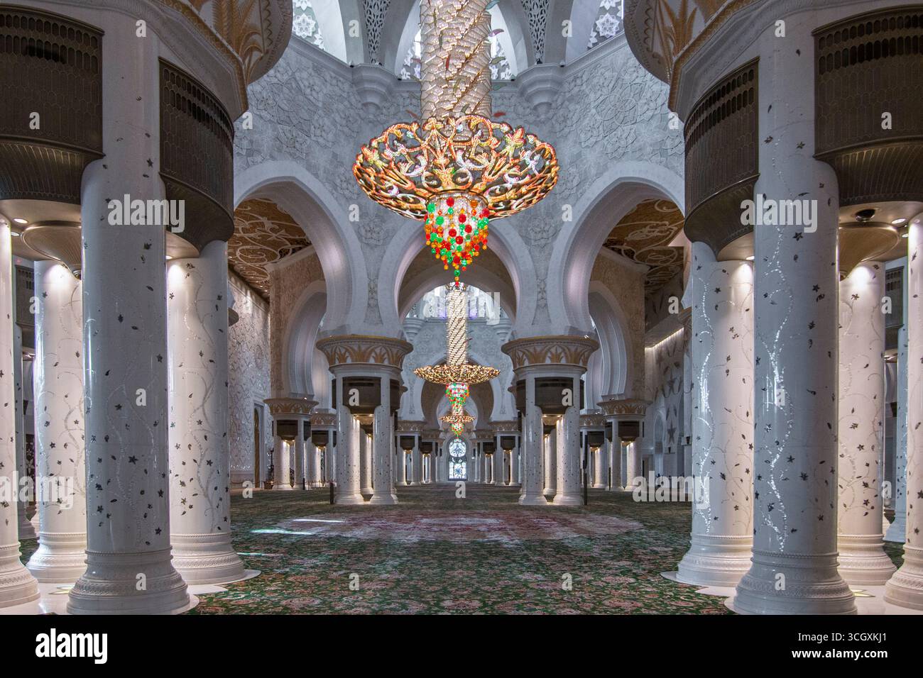 Emirati Arabi Uniti - Abu Dhabi - Central Aisle Perspective - lampadari allineati sotto archi svettanti e portici di colonne sul vasto tappeto Foto Stock