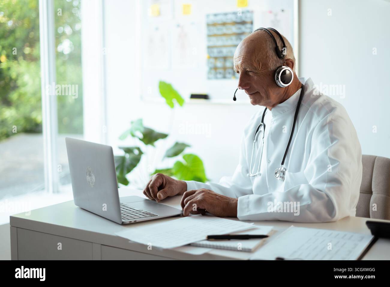 Medico anziano che lavora online consultando paziente nel concetto di telemedicina Foto Stock