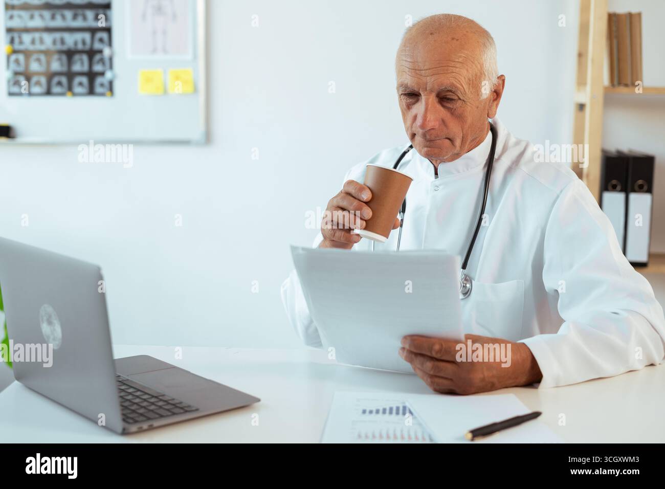 medico di sesso maschile che lavora con documenti che bevono caffè durante il turno in clinica, copia spazio Foto Stock