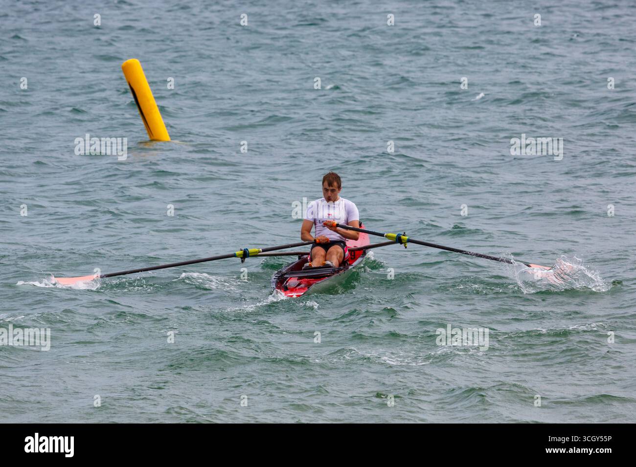 Studland, Dorset Regno Unito. 30 agosto 2025. Il primo giorno dei due giorni di gare del più grande British Rowing Beach Sprint Championships (BRBSC) si svolge a Knoll Beach, Studland, con un numero record di canottieri. Partendo da uno sprint sulla spiaggia per una persona per ogni equipaggio, i vogatori proseguono per 250 m in mare, sfrecciando intorno a due boe, prima di girarne un terzo e tornare direttamente a riva, prima dello sprint finale sulla spiaggia verso un cicalino. Due barche vanno testa a testa in gare con la barca più veloce che progredisce e il secondo posto viene messo fuori combattimento. Crediti: Carolyn Jenkins/Alamy Live News Foto Stock