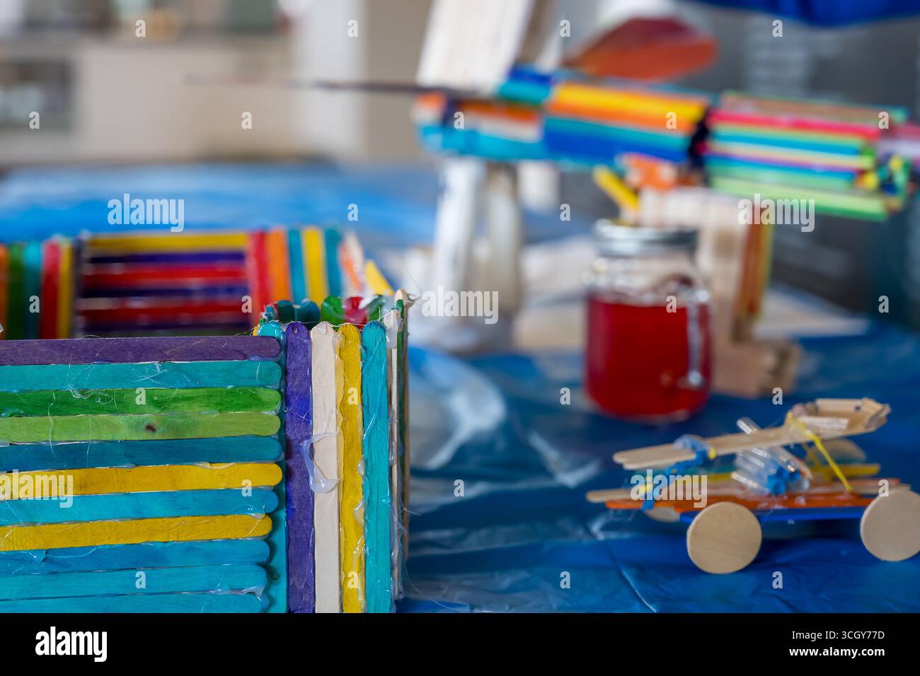 Creazione di giocattoli e strutture colorate utilizzando bastoncini a pistoncino e altri materiali in uno spazio interno luminoso Foto Stock
