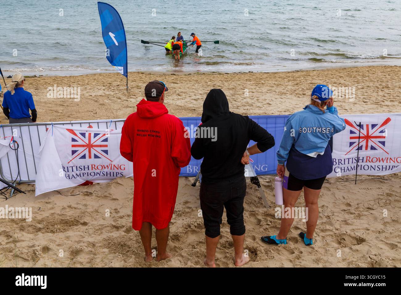Studland, Dorset Regno Unito. 30 agosto 2025. Il primo giorno dei due giorni di gare del più grande British Rowing Beach Sprint Championships (BRBSC) si svolge a Knoll Beach, Studland, con un numero record di canottieri. Partendo da uno sprint sulla spiaggia per una persona per ogni equipaggio, i vogatori proseguono per 250 m in mare, sfrecciando intorno a due boe, prima di girarne un terzo e tornare direttamente a riva, prima dello sprint finale sulla spiaggia verso un cicalino. Due barche vanno testa a testa in gare con la barca più veloce che progredisce e il secondo posto viene messo fuori combattimento. Crediti: Carolyn Jenkins/Alamy Live News Foto Stock