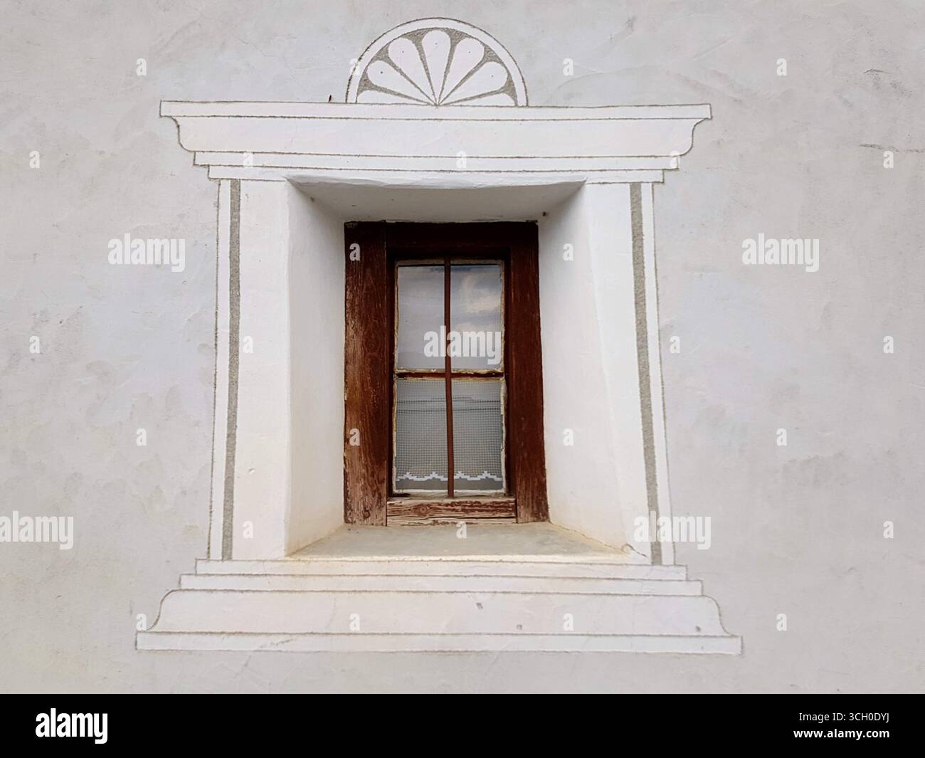 Tipica piccola finestra Engadina con una cornice in legno, bordo decorativo ornamentale e parete bianca intonacata, Svizzera Foto Stock