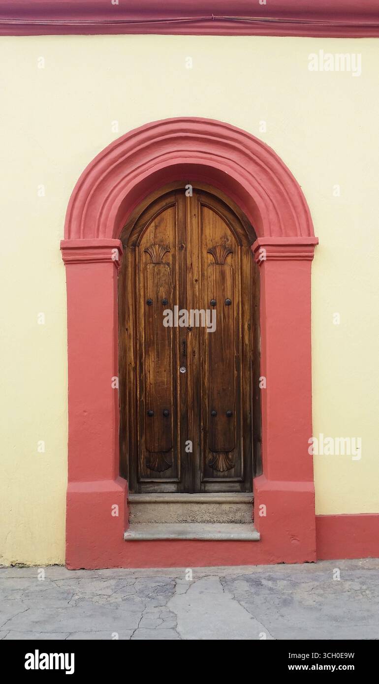 Vecchie porte d'ingresso in legno nostalgiche con autentico fascino messicano, decorate con archi colorati e colonne ornate Foto Stock
