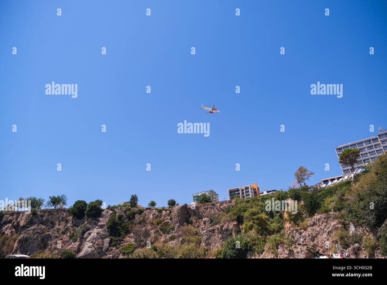 belek, Turkiye, 27.07.2025 aereo che vola sopra edifici residenziali su una scogliera. Viaggi, vacanze, vacanze, stagione estiva, turismo. Foto Stock