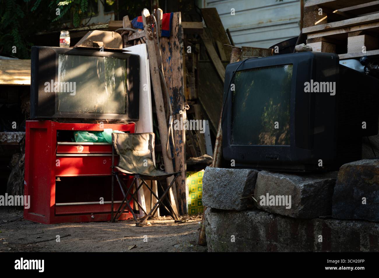 Ingresso a un rifugio all'aperto per senzatetto fiancheggiato da due vecchi televisori rotti. Foto Stock