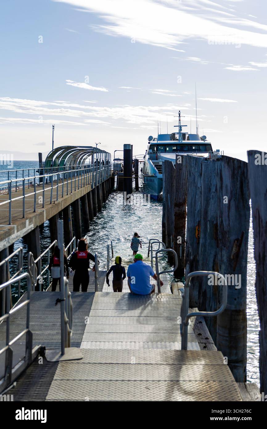 le persone sedute su una barca da crociera sul molo attraccavano paddling wet suit giubbotti salvagente vacanze rilassanti viste sull'oceano blu tranquillo paradiso acquatico avventura sulla barriera corallina Foto Stock