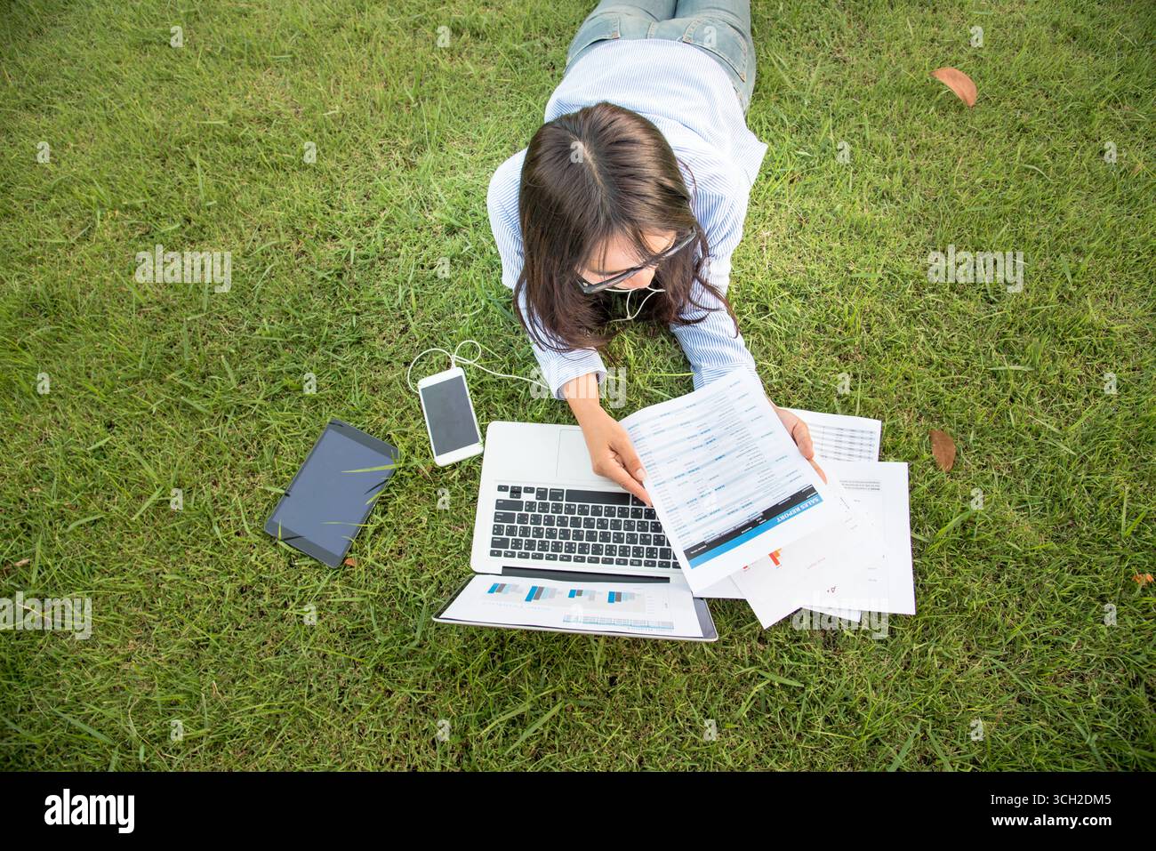 Donna asiatica stendersi parco verde giardino utilizzando computer portatile che lavora all'aperto casa ufficio. La felicità della donna sorride lavorando freelance su un notebook. Giovani donne Univer Foto Stock