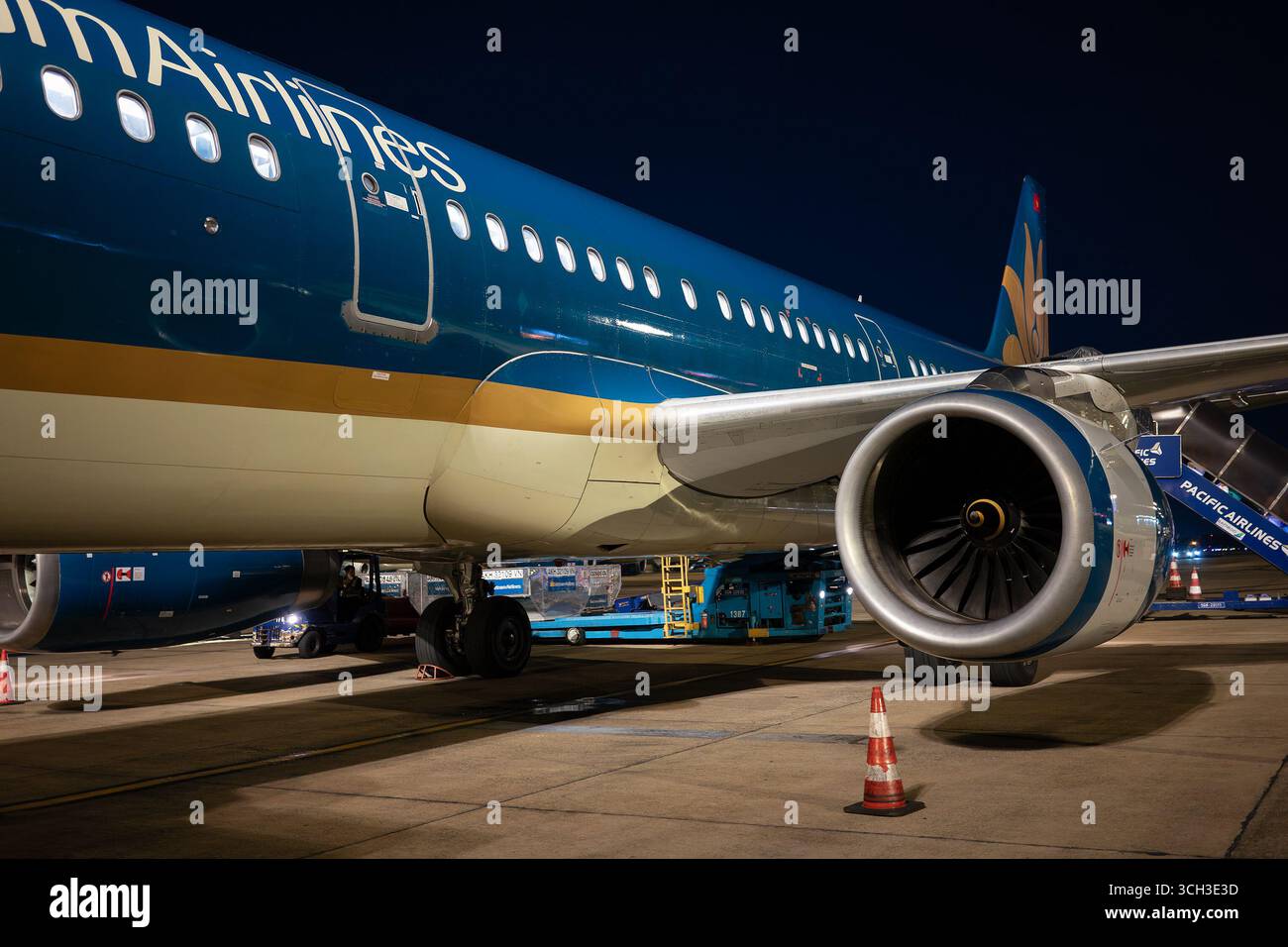 Ho chi Minh City, Vietnam - 10 maggio 2025: Vista dell'ala e del motore di un aeromobile Airbus A321 parcheggiato sull'asfalto di notte. Foto Stock