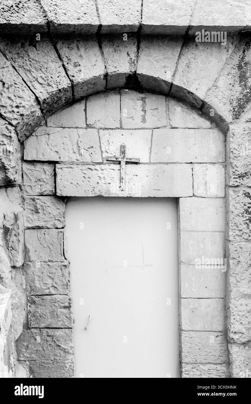 Ingresso in pietra rustica con simbolo a croce in bianco e nero Foto Stock