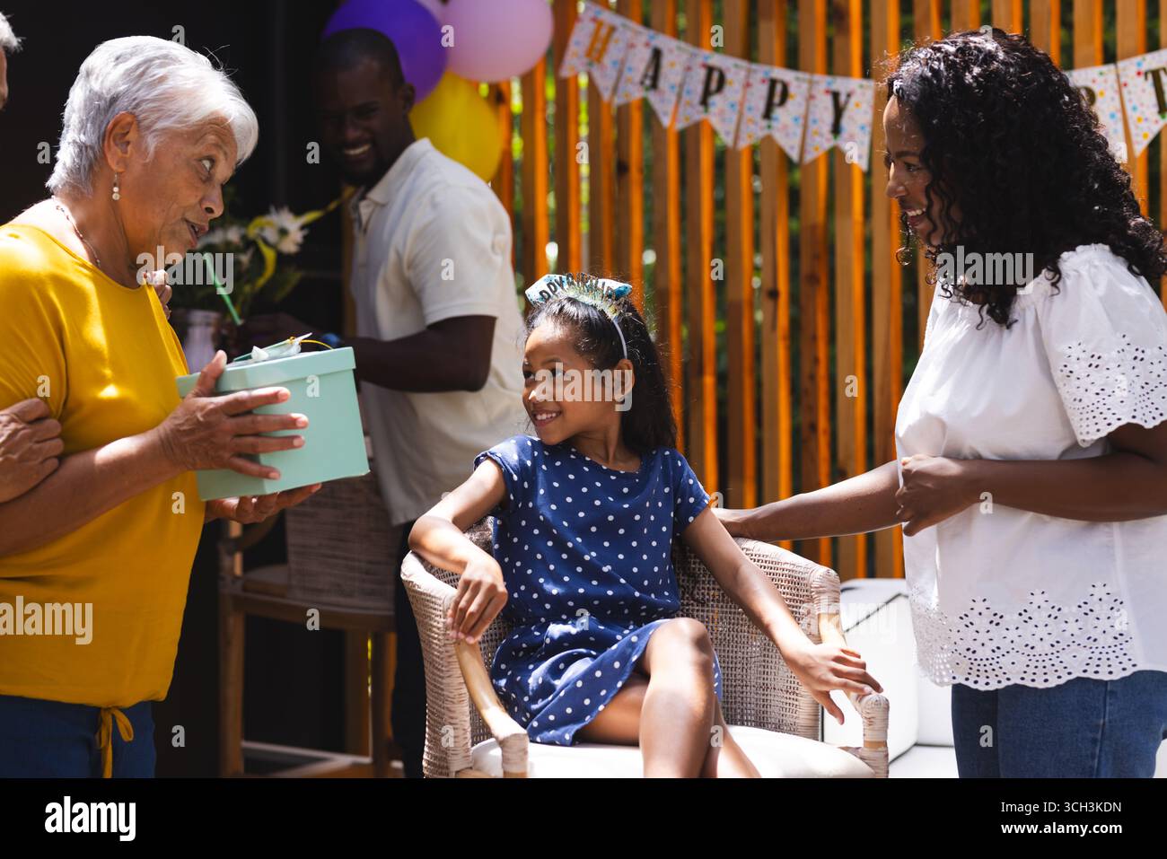 Alla festa, la nonna fa un regalo di compleanno a una ragazza sorridente alla felice festa di famiglia in giardino Foto Stock