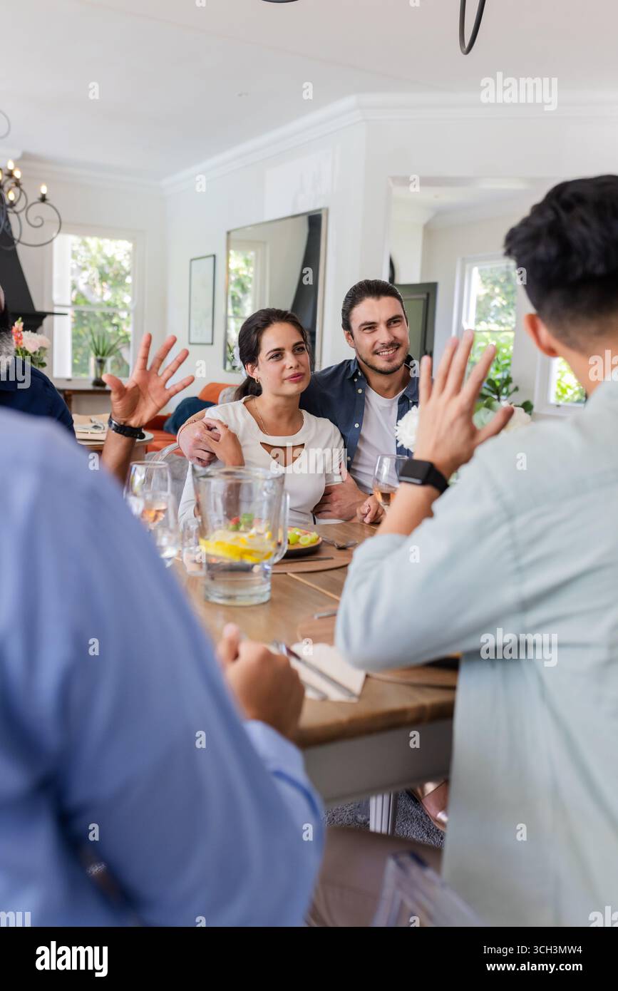 Festeggiamo un piccolo matrimonio informale a casa, gli amici che conversano intorno al tavolo da pranzo, a casa Foto Stock