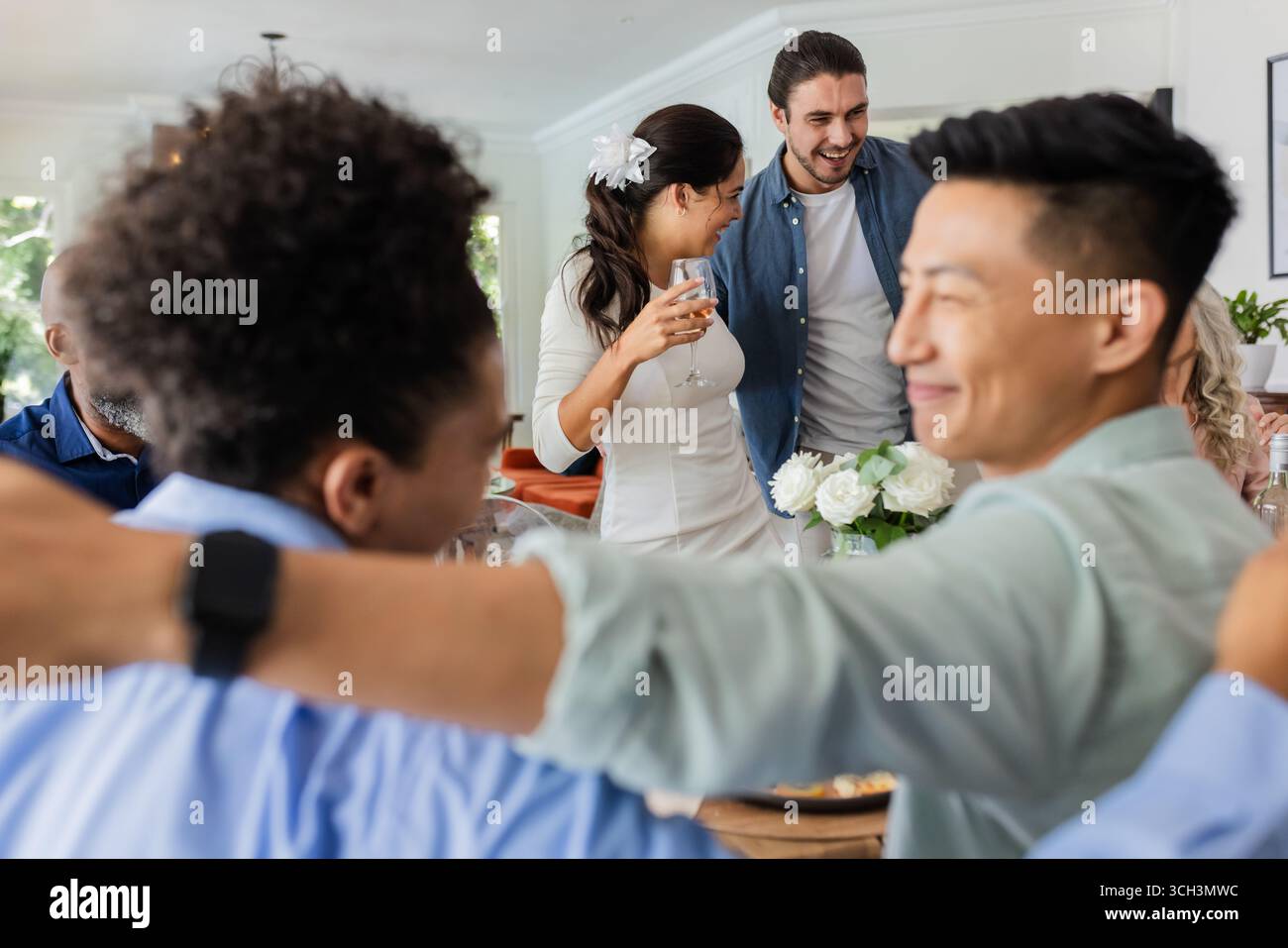 Ospiti che festeggiano insieme in un piccolo ricevimento di nozze informale, sorridendo e godendo momenti, a casa Foto Stock Ospiti che festeggiano insieme in un piccolo ricevimento di nozze informale, sorridendo e godendo momenti, a casa Foto Stock
