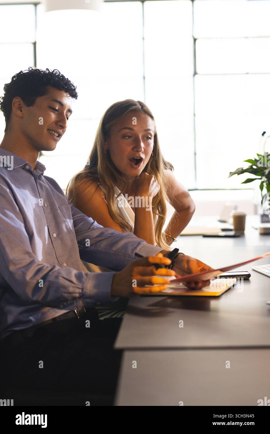 Colleghi che discutono di progetti alla scrivania dell'ufficio, condividono idee e sorridono Foto Stock