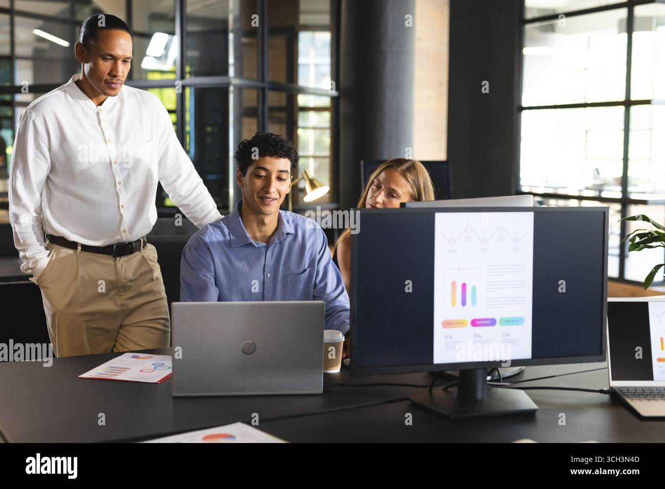 Team aziendale che collabora al progetto con notebook e grafici in uffici moderni Foto Stock