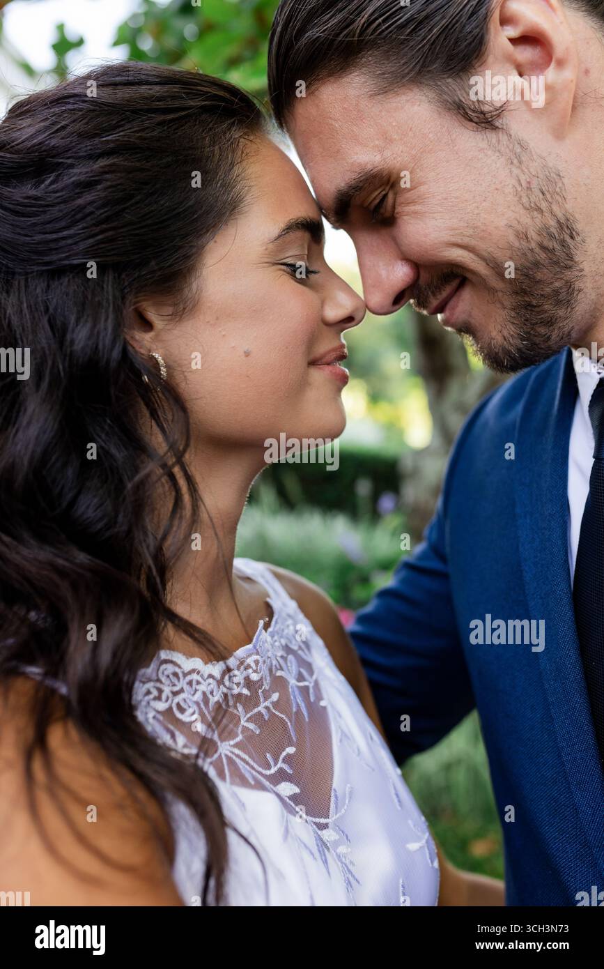 La sposa e gli sposi condividono momenti intimi all'aperto, sorridendo e abbracciando delicatamente Foto Stock