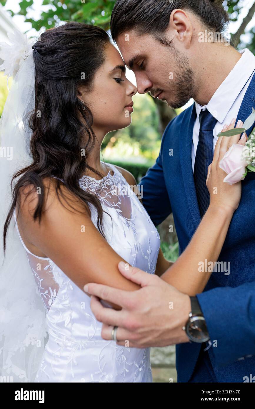 Gli sposi e gli sposi abbracciano tenerezza all'aperto, condividendo momenti romantici insieme Foto Stock