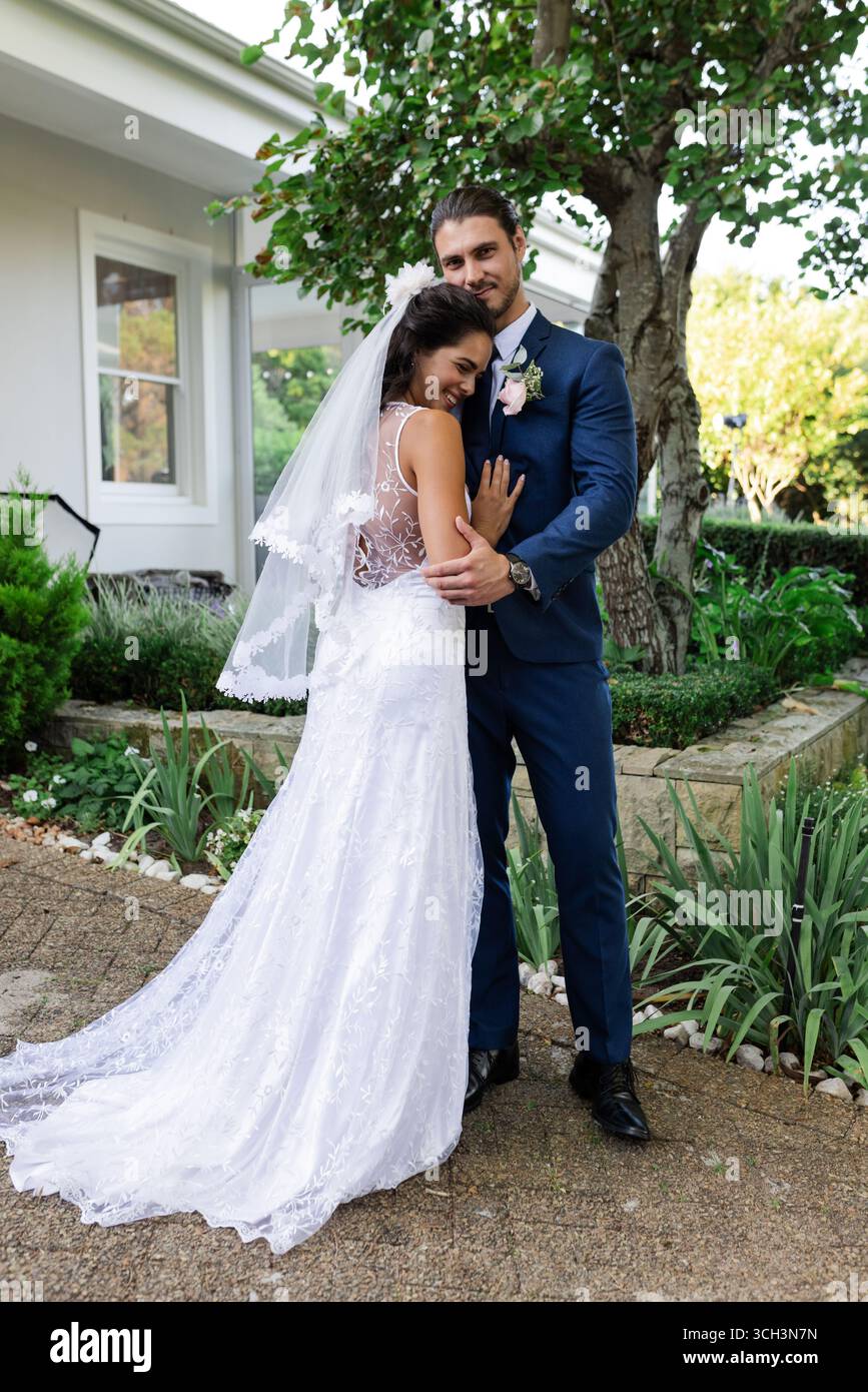Sposi e sposi che abbracciano all'aperto, celebrano l'amore il giorno del matrimonio Foto Stock
