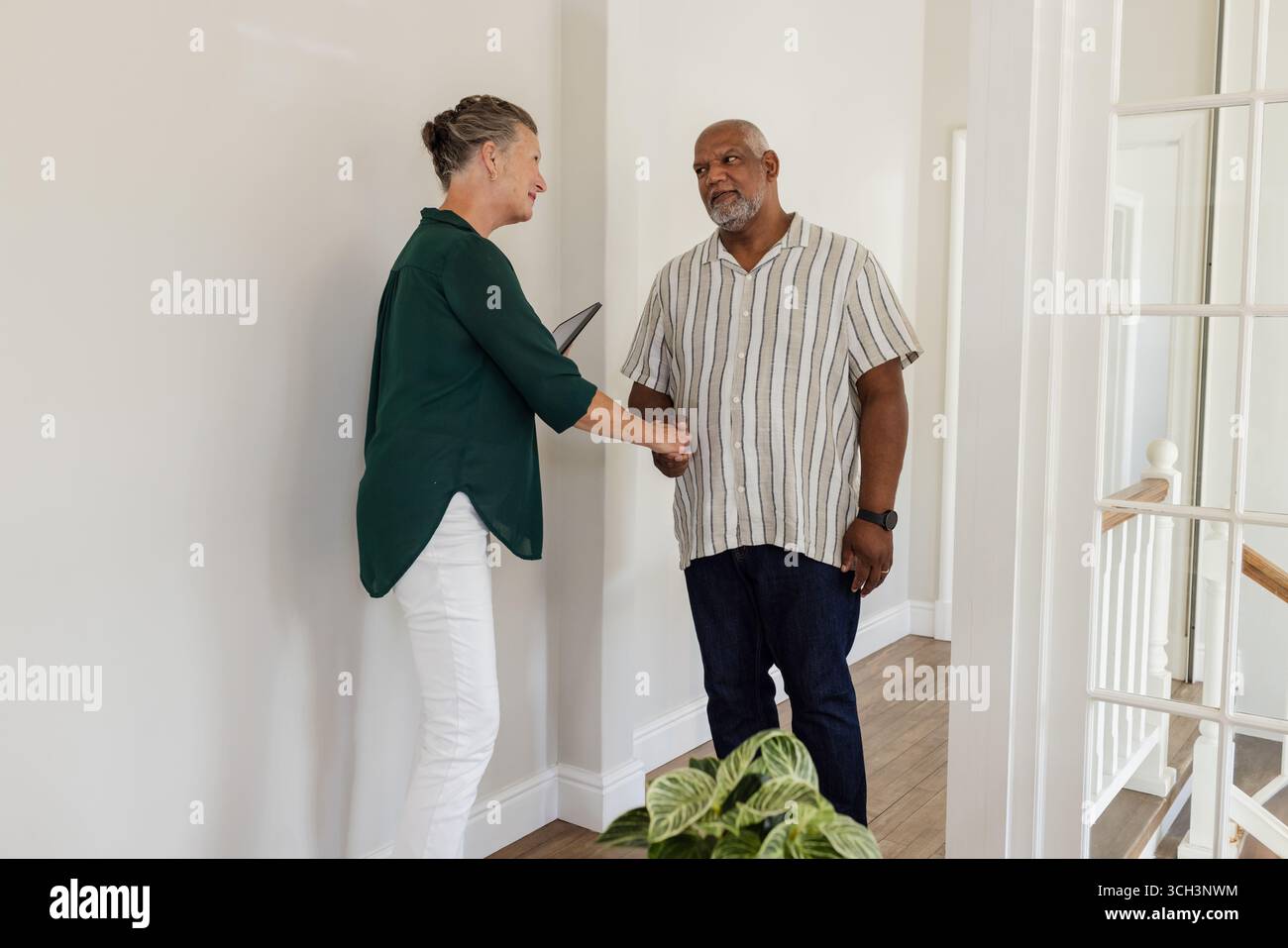 Coppia senior che stringe la mano calorosamente nel corridoio, celebrando un'occasione speciale Foto Stock
