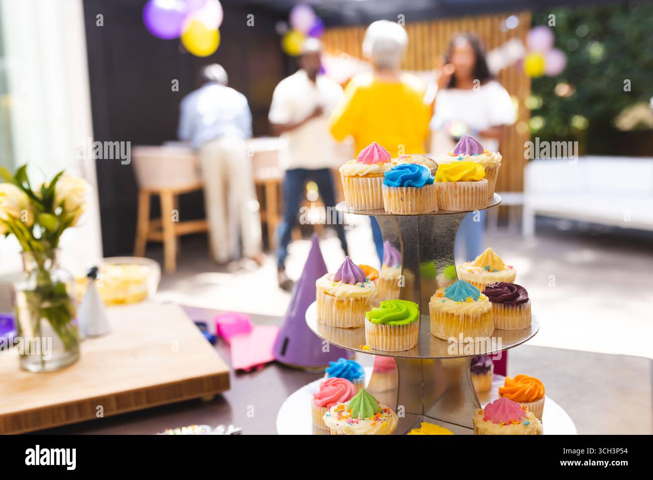 Alla festa, Cupcakes in mostra alla felice riunione di famiglia, persone che festeggiano in sottofondo Foto Stock