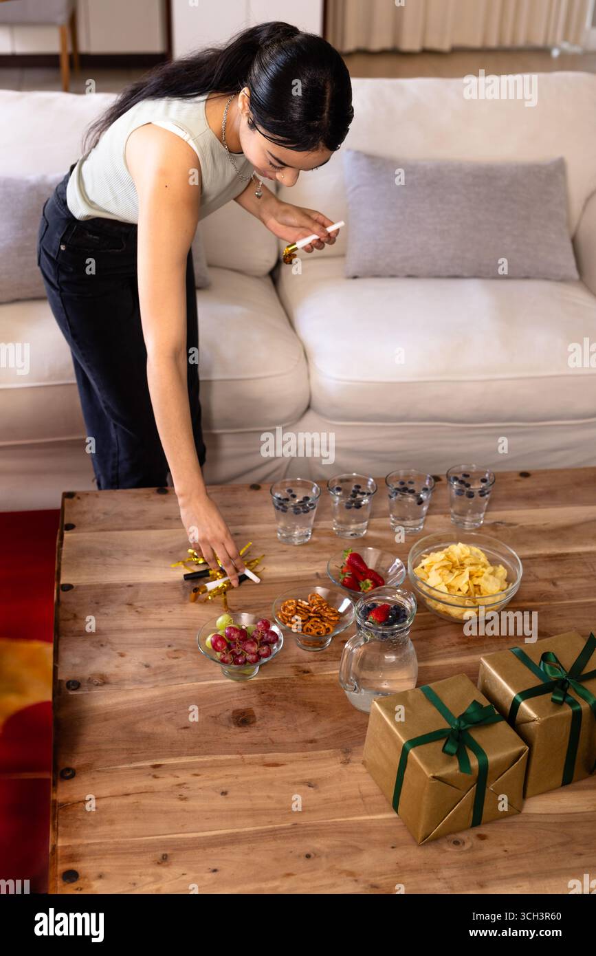 Tavolo in legno con ciotole per spuntini, bicchieri da acqua e scatole regalo in oro nel soggiorno, spazio per fotocopie Foto Stock