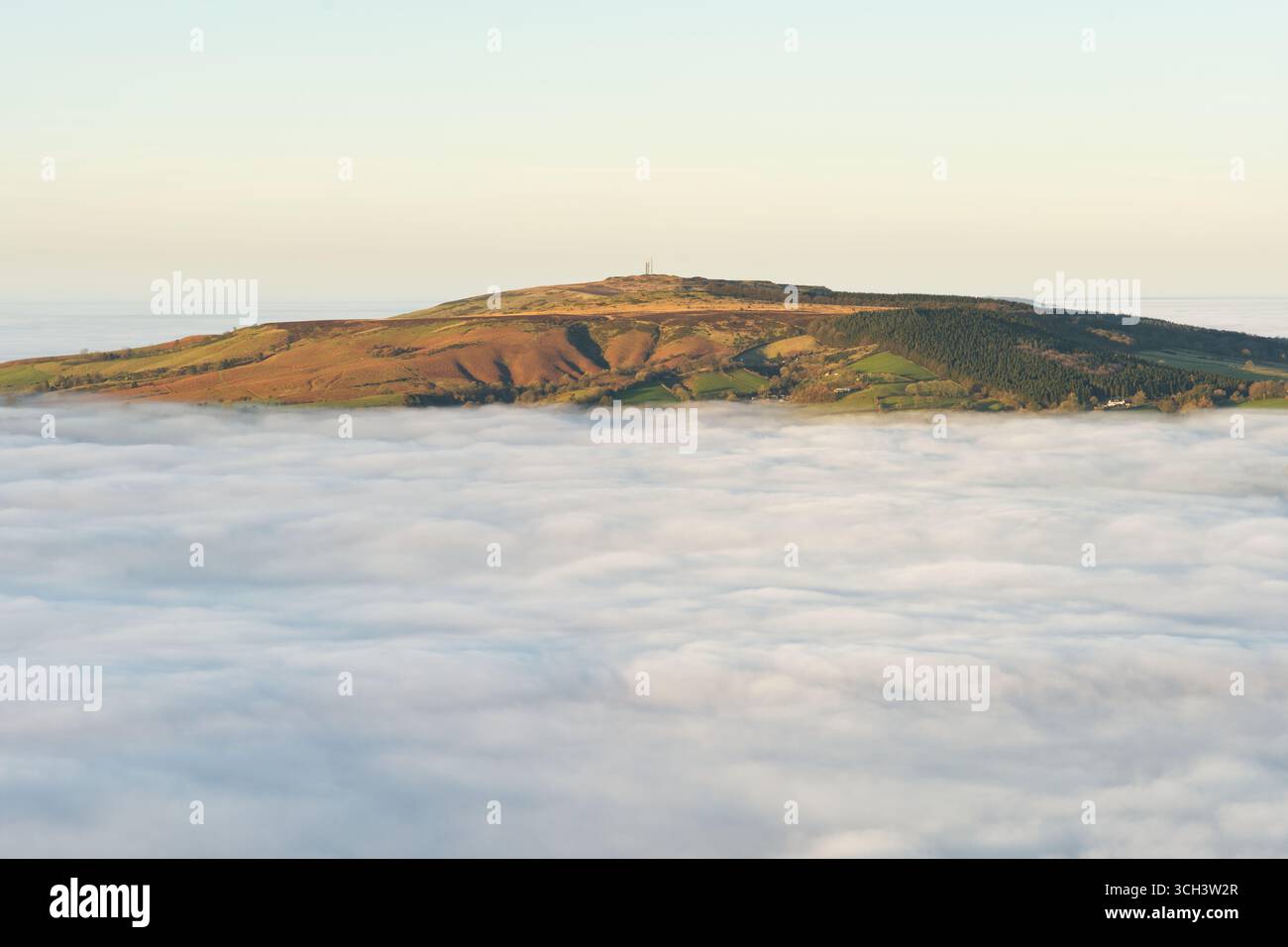 Brown Clee Hill, il punto più alto dello Shropshire, visto sopra un'inversione di nuvole dalla vicina Titterstone Clee Hill. Foto Stock