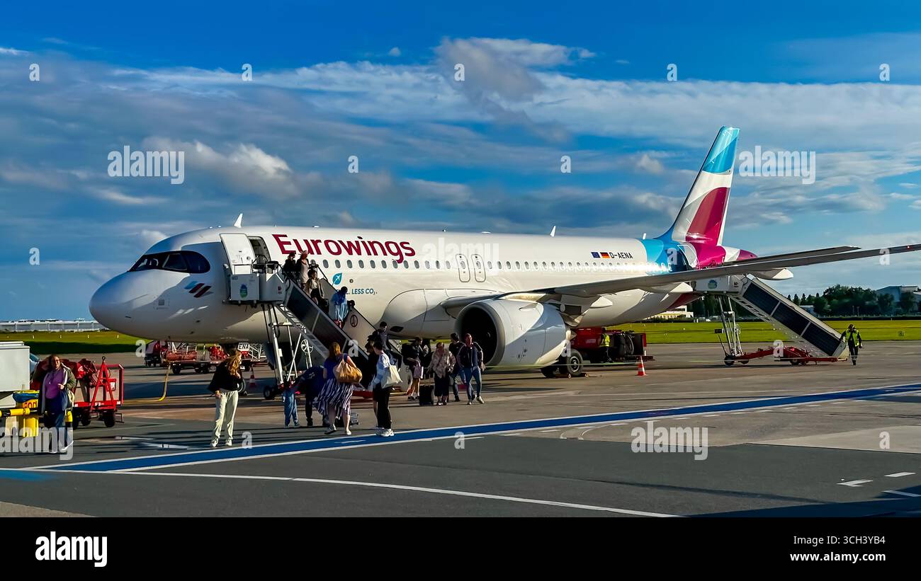 Un aeromobile Airbus A320 di Eurowings sull'asfalto con passeggeri imbarcati utilizzando una scala mobile in un aeroporto tedesco. Foto Stock