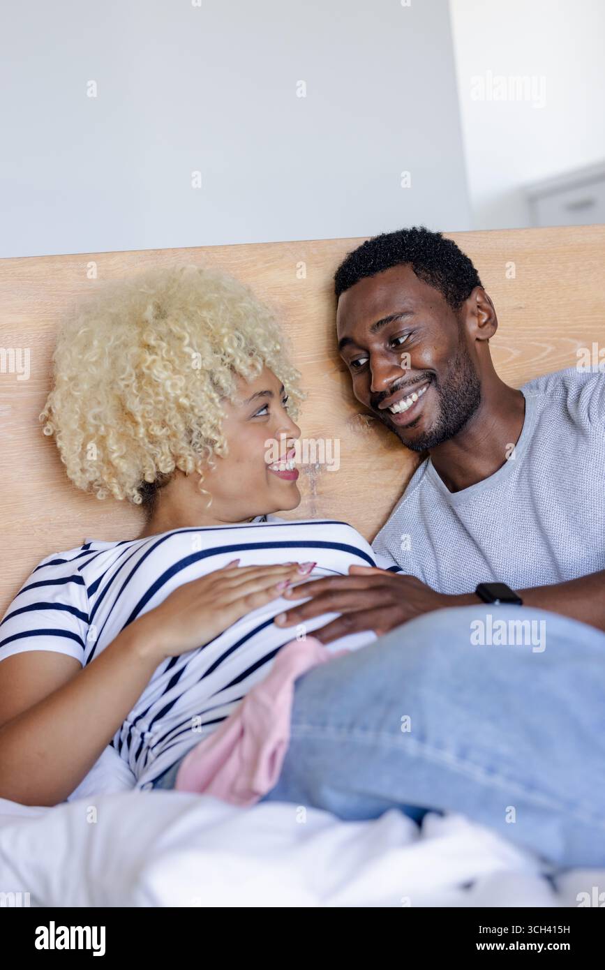 Coppia che si rilassa sul letto, sorridendo e godendo momenti di qualità insieme a casa Foto Stock