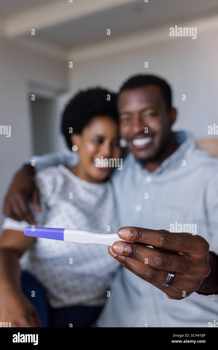 Coppia afroamericana con gioia che tiene il test di gravidanza positivo a casa Foto Stock
